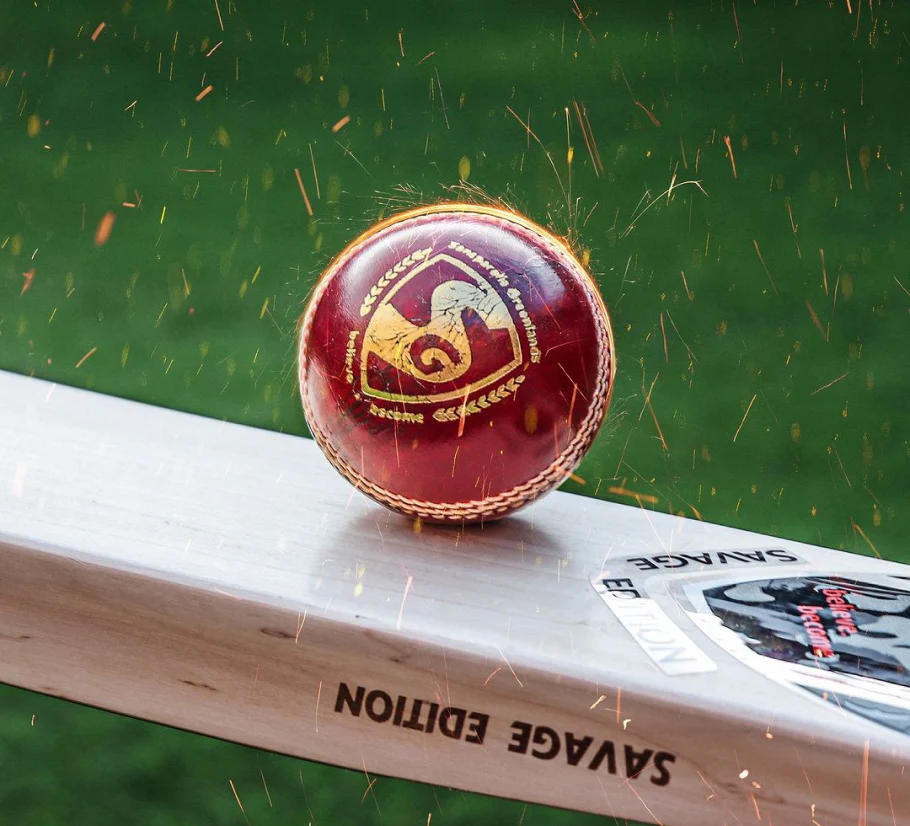 SG Test Red four-piece leather cricket ball with prominent hand-stitching and official SG gold branding.